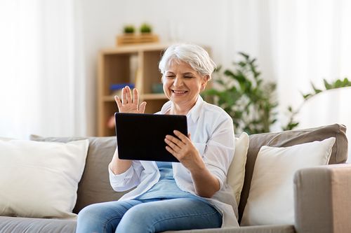 A woman sitting on top of a couch holding an ipad.