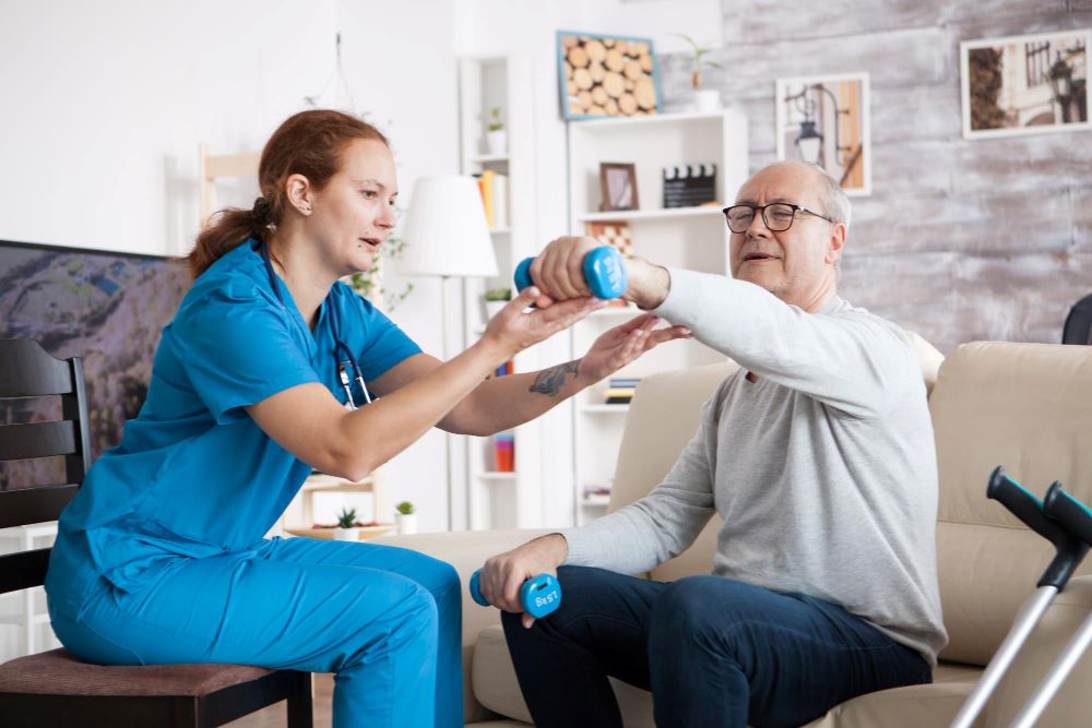 A nurse is helping an older man exercise.