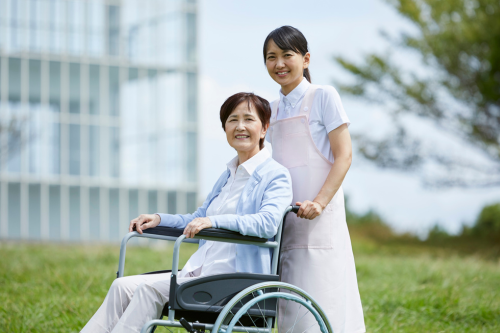 A skilled nurse or therapist gently assisting an elderly patient in a home setting — maybe checking vitals, explaining medication, or offering a reassuring smile.