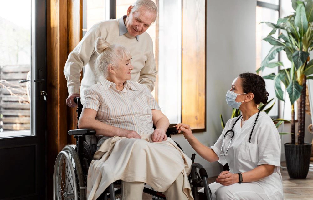 A doctor and nurse talking to an older woman in a wheelchair.
